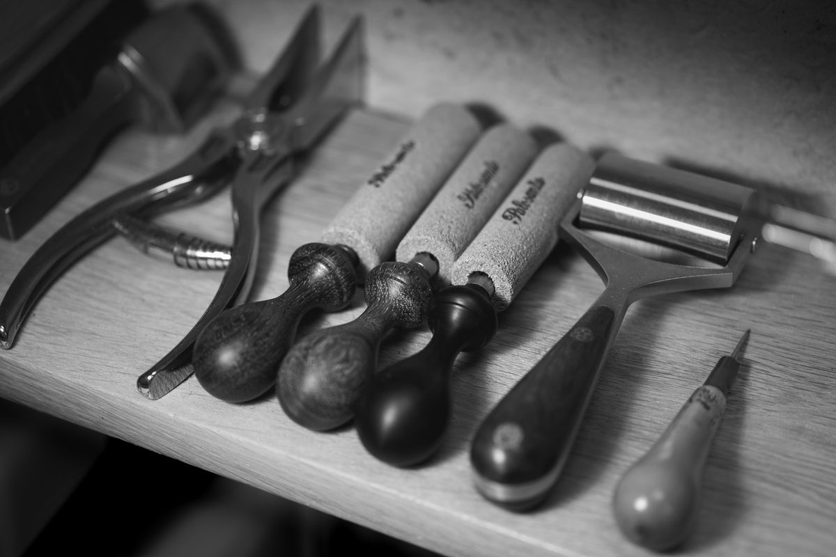 différents outils de travail à la main comme des pinces, rouleau, abat-carre et emporte pièces.